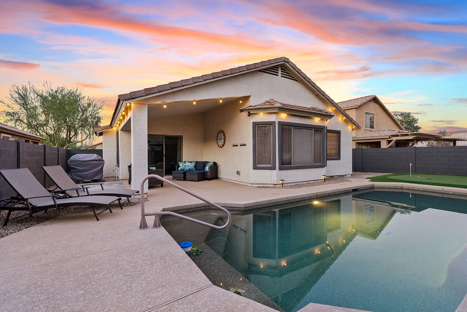 A house with a covered patio, outdoor seating, and a swimming pool.