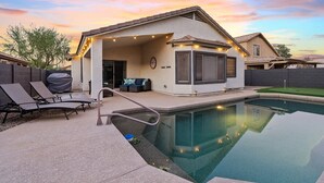 Ein Haus mit überdachter Terrasse, Sitzgelegenheit im Freien und einem Swimmingpool.