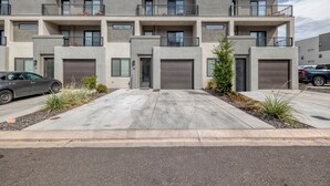 A modern multi-story residential building with a symmetrical facade, large garage doors, and a landscaped driveway. - Newly furnished 5bd/4.5ba Townhome - The Vue 30 welcomes you! (St. George)