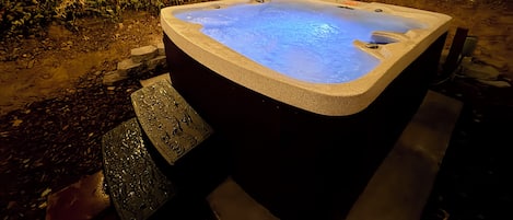 Ein Whirlpool in einem Garten mit Holzzaun und Lichterkette.