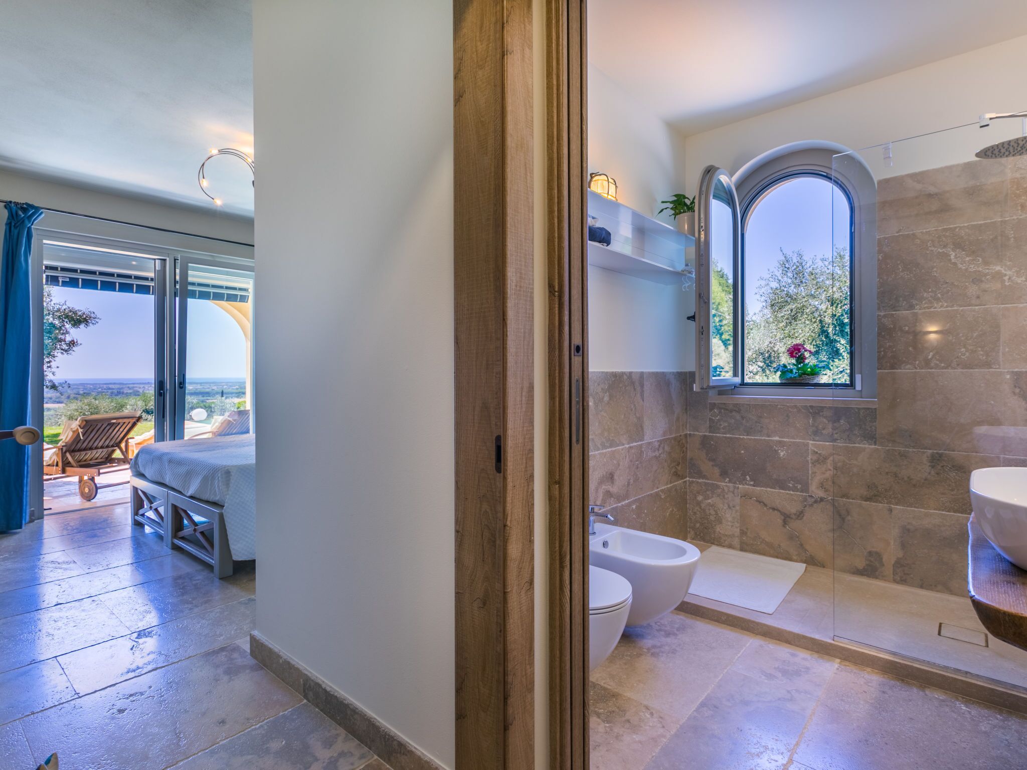 Un baño moderno con bañera, bidé y un amplio ventanal con vistas al exterior.