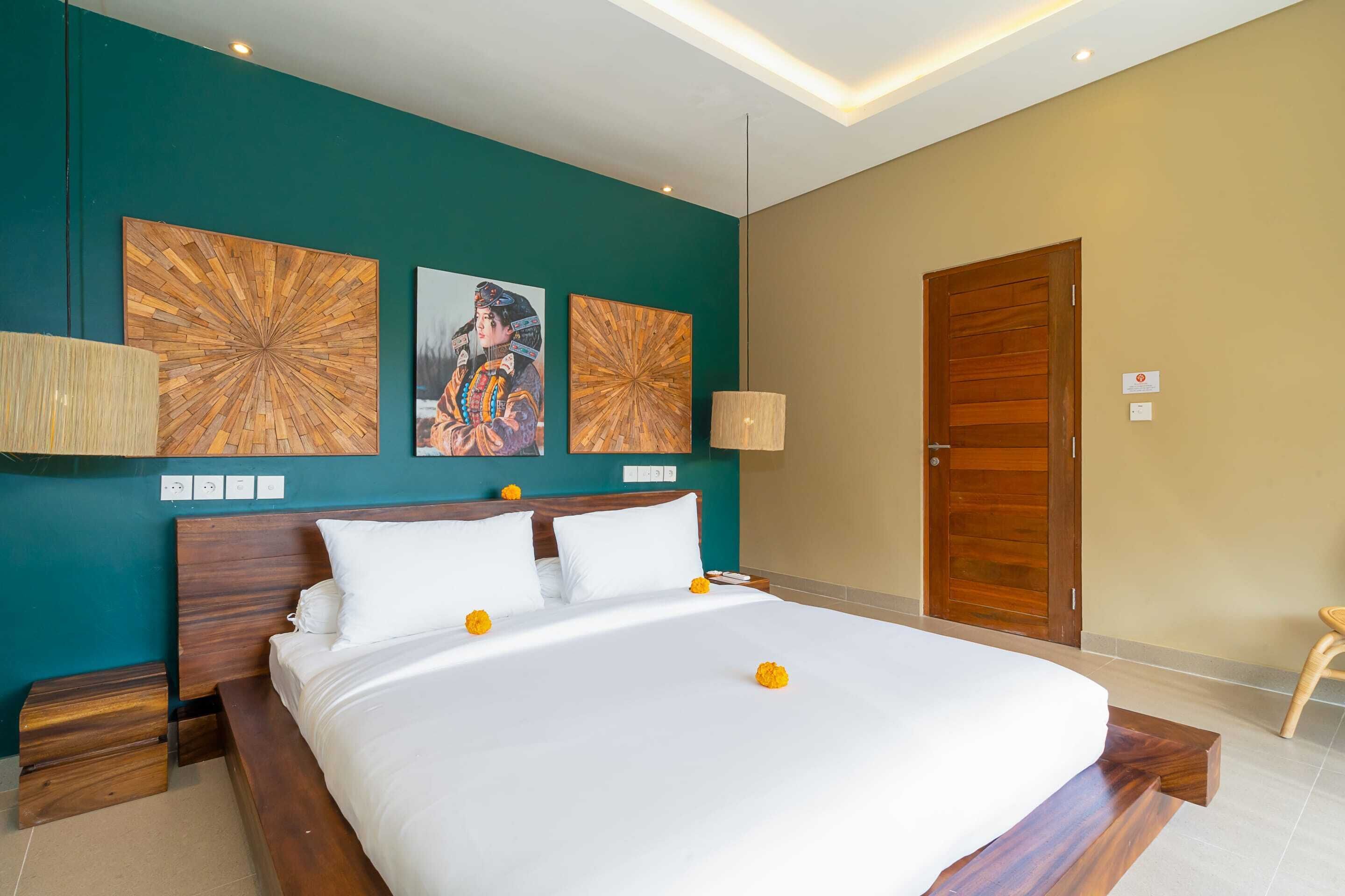 Ein Hotelzimmer mit einem großen Bett, einem Holzkopfteil, zwei Wandlampen und zwei Holzbildern.