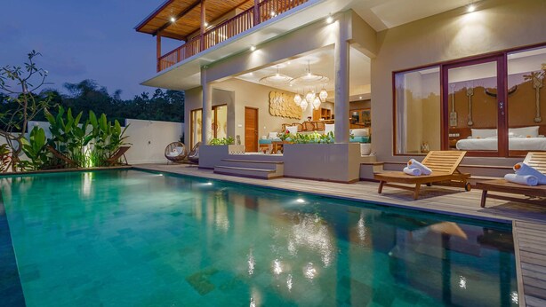 A modern house with a swimming pool, outdoor seating, and a well-lit interior. - Villa Canopy (Tabanan)