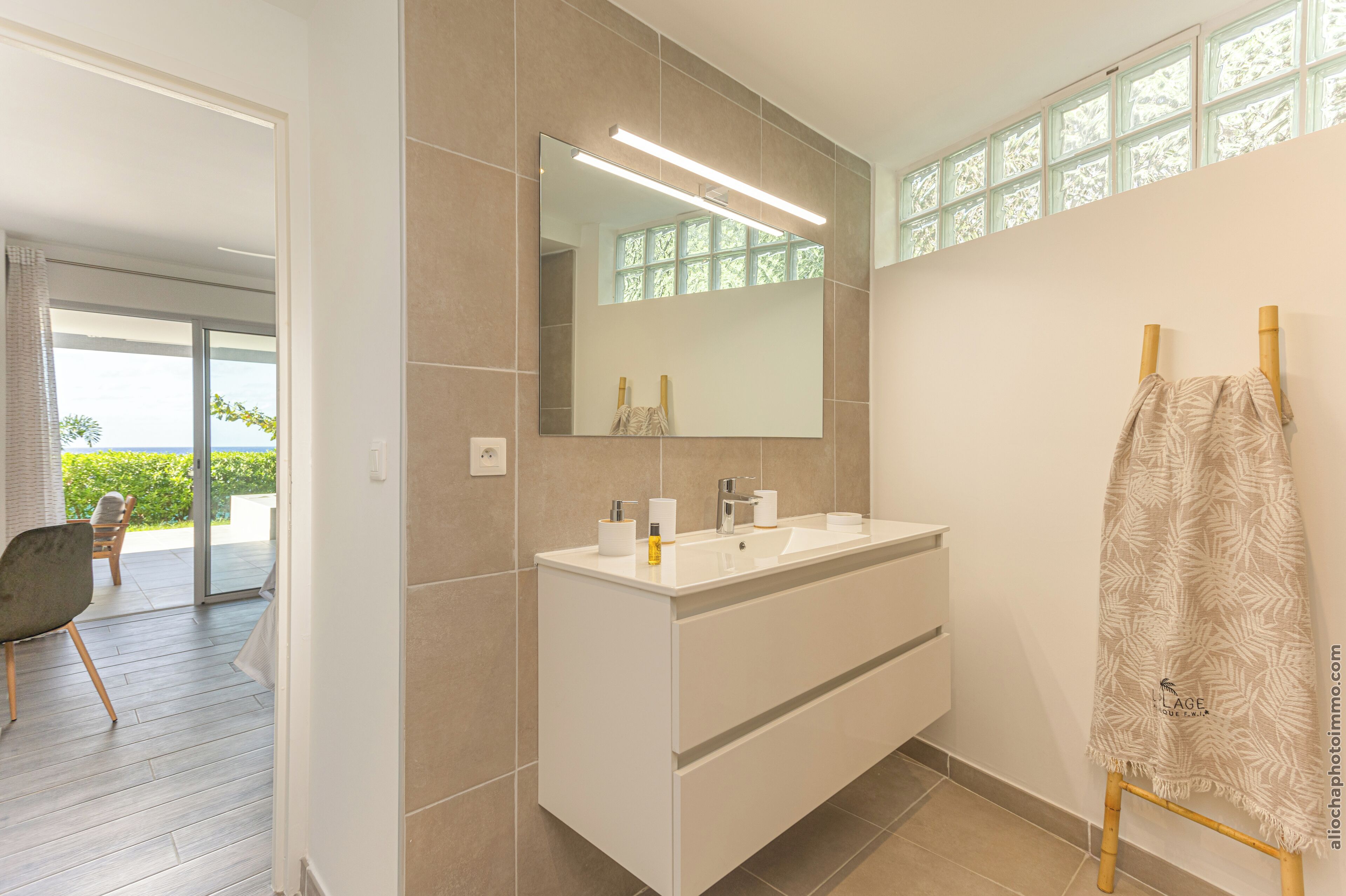 A modern bathroom with a large mirror, white vanity, and a towel rack.