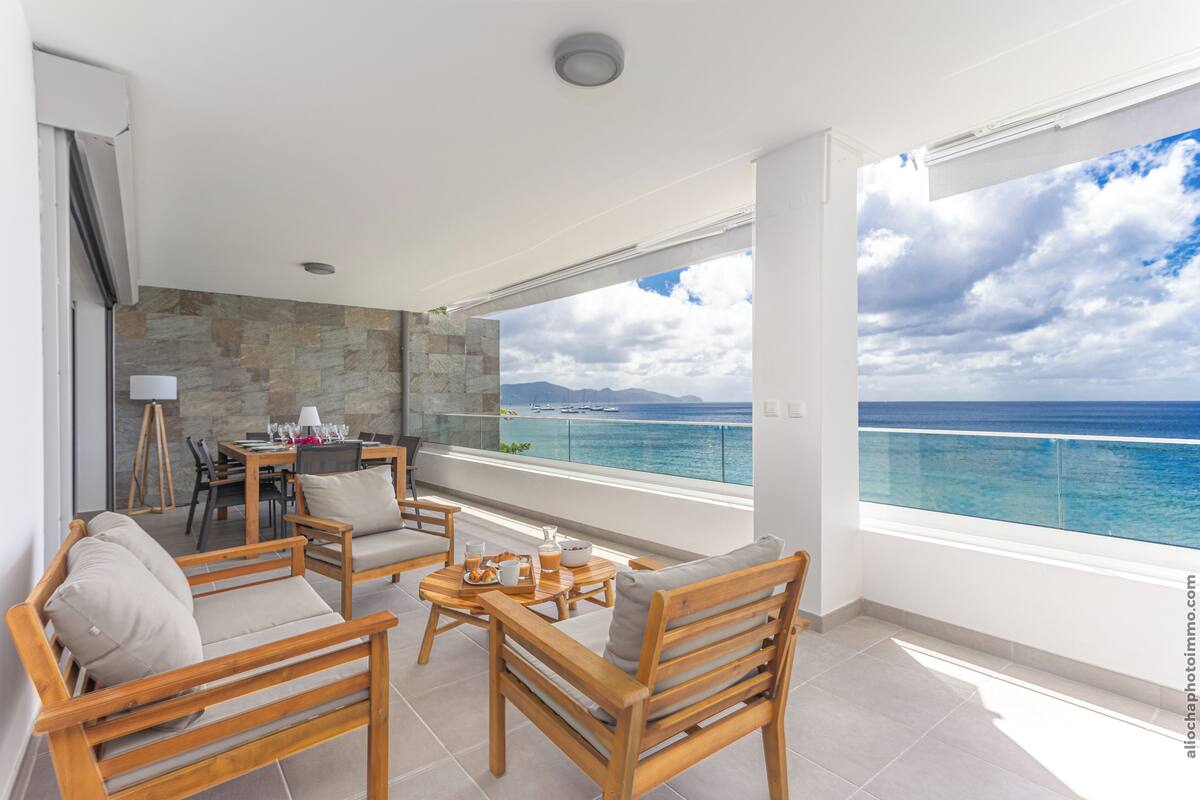 Ein Balkon mit Steinmauer, Holzmöbeln und einem Tisch mit Frühstücksleckereien.