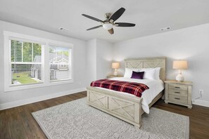 A bedroom with a bed, two bedside tables, a ceiling fan, and a window with blinds.