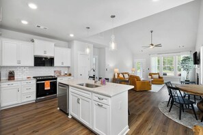 A modern kitchen with white cabinets, a central island, and a dining area with a wooden table and chairs.