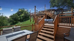Eine Holzterrasse mit Sitzgelegenheiten im Freien und einer Treppe zu einem überdachten Bereich.