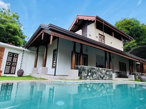 Une maison à deux étages avec une piscine à l’avant.