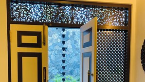 An open door leading to a room with a table and chairs, a decorative screen, and a view of a garden with a water feature. - Thaprobana Villa Tangalle Private Villa (Tangalle)