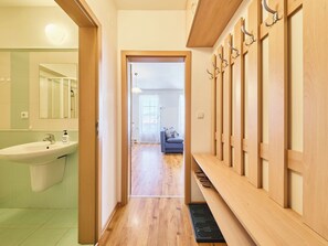 A hallway with a wooden bench, a sink, and a mirror.