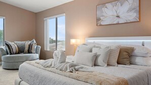 A bedroom with a bed, a sofa, a nightstand, and a window.