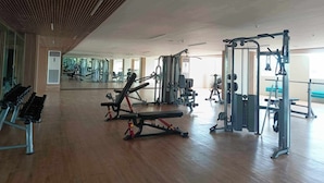 A spacious gym with various exercise equipment, a large mirror, and a wooden ceiling.