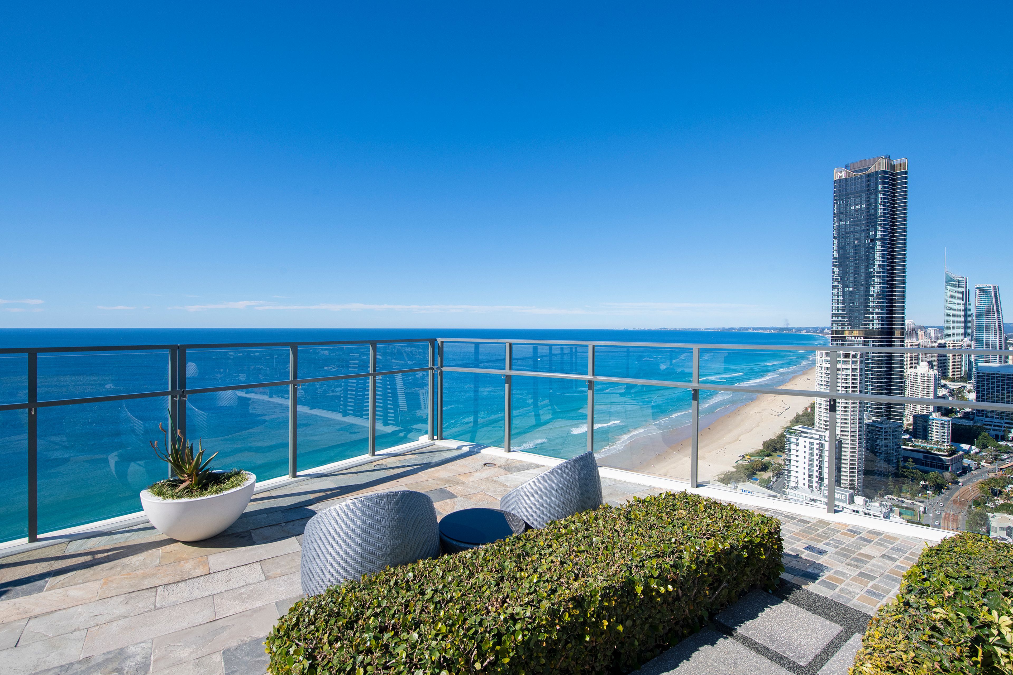 A balcony with a view of the ocean and a cityscape.
