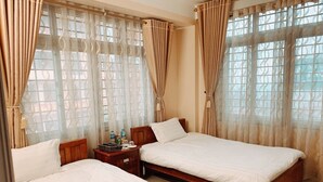 A hotel room with two beds, a wooden nightstand, and a window with patterned curtains. - Hoang Hiep Hotel Sapa - by Bay Luxury (Sa Pa)