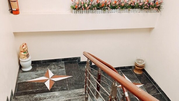 A staircase with a metal handrail, a decorative star pattern on the floor, a small figurine, and a fire extinguisher. - Hoang Hiep Hotel Sapa - by Bay Luxury (Sa Pa)