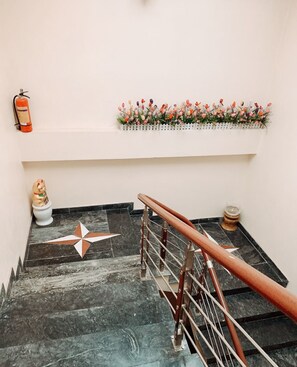A staircase with a metal handrail, a decorative star pattern on the floor, a small figurine, and a fire extinguisher. - Hoang Hiep Hotel Sapa - by Bay Luxury (Sa Pa)