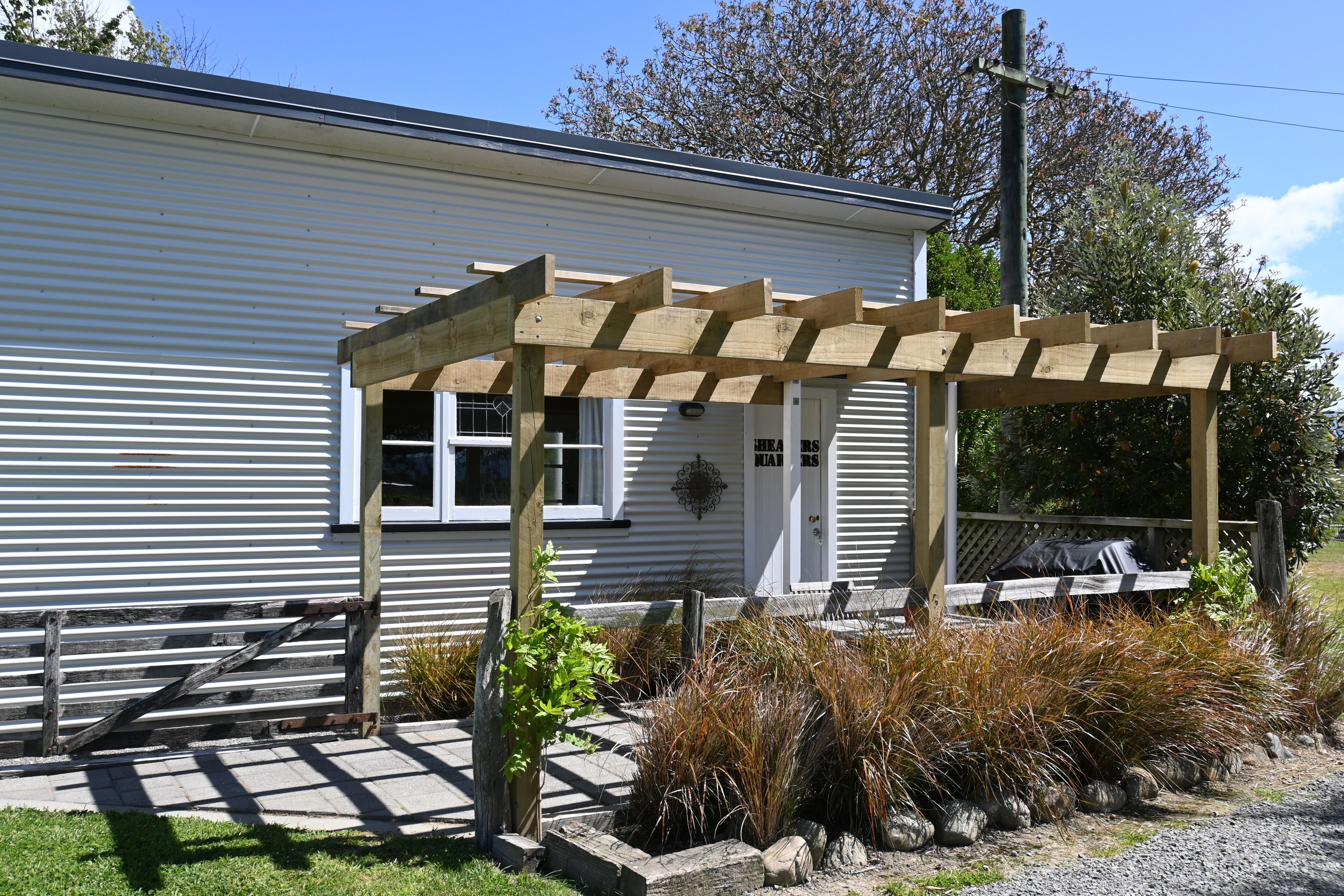 A house with a wooden pergola, a front door, and a small porch area.