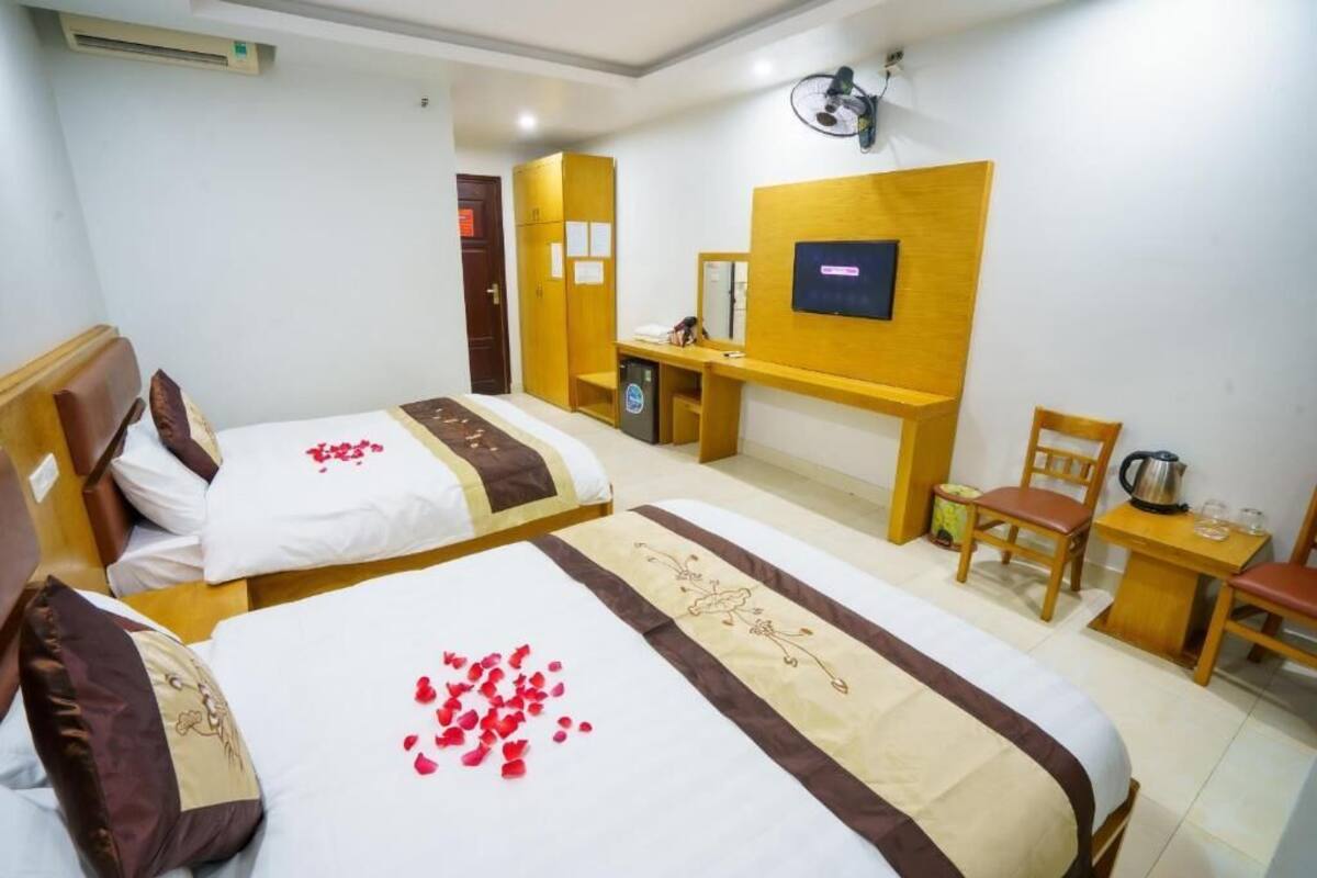 Habitación de hotel con dos camas, un escritorio, una silla, un televisor y una mesita con una tetera.