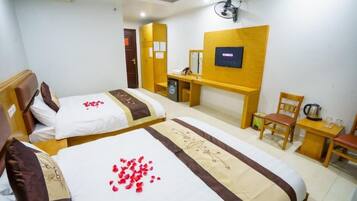 Habitación de hotel con dos camas, un escritorio, una silla, un televisor y una mesita con una tetera.