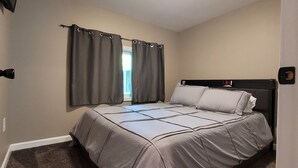A bedroom with a bed, a window with curtains, a ceiling light, and a wall clock. - Charming 1-bd house in Downtown Farmington, 1block from Police & Fire stations (Farmington)