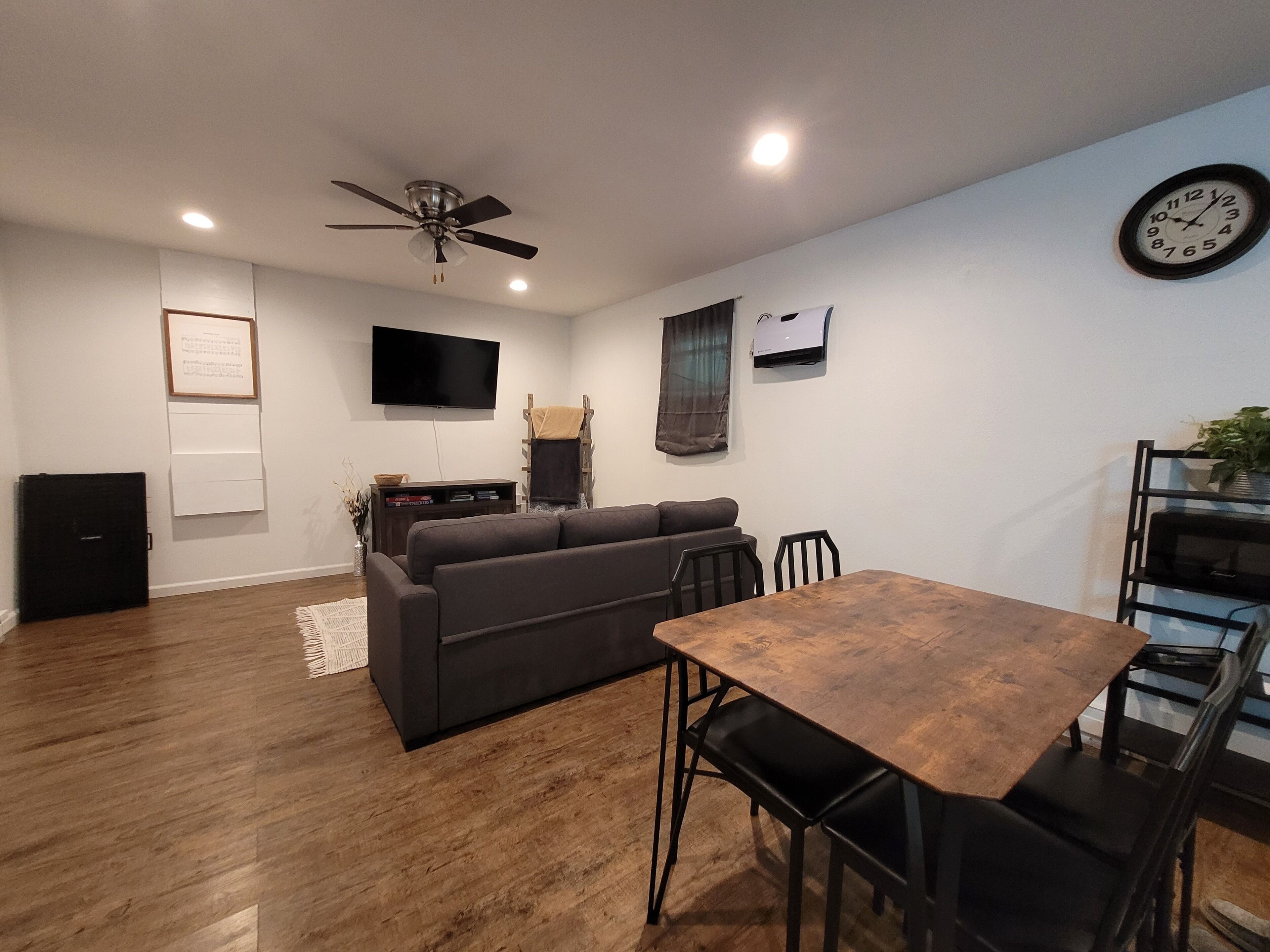 Un salon moderne avec un canapé, une table à manger en bois et un ventilateur de plafond.
