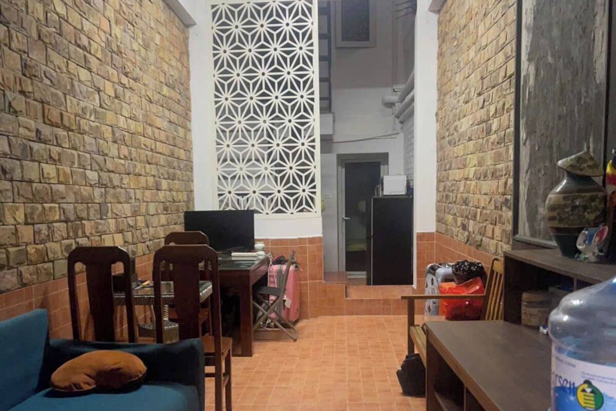 Una sala de estar acogedora con un sofá azul, sillas de madera, una mesita y un panel decorativo en la pared.