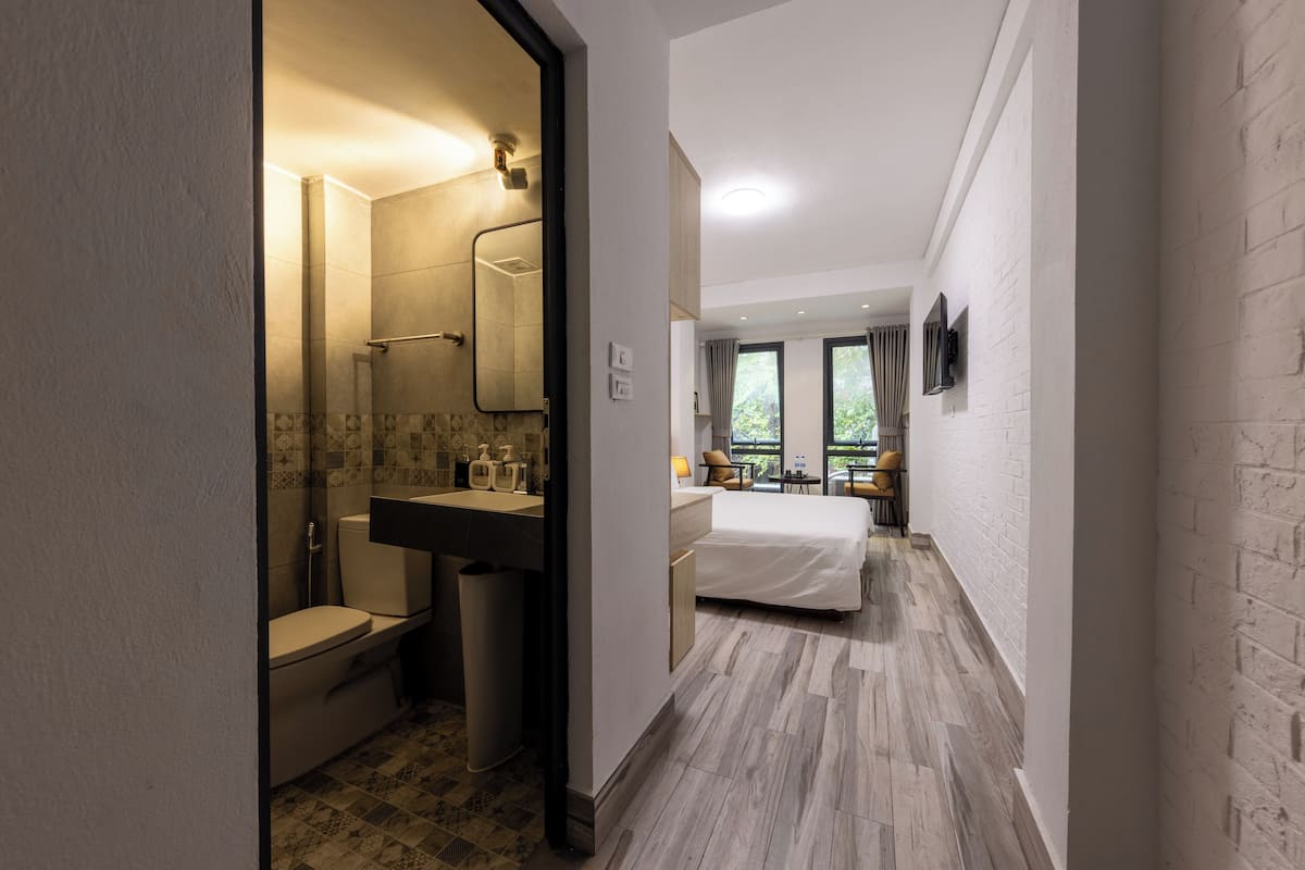 Una habitación de hotel moderna con baño, cama, escritorio y vistas al exterior.