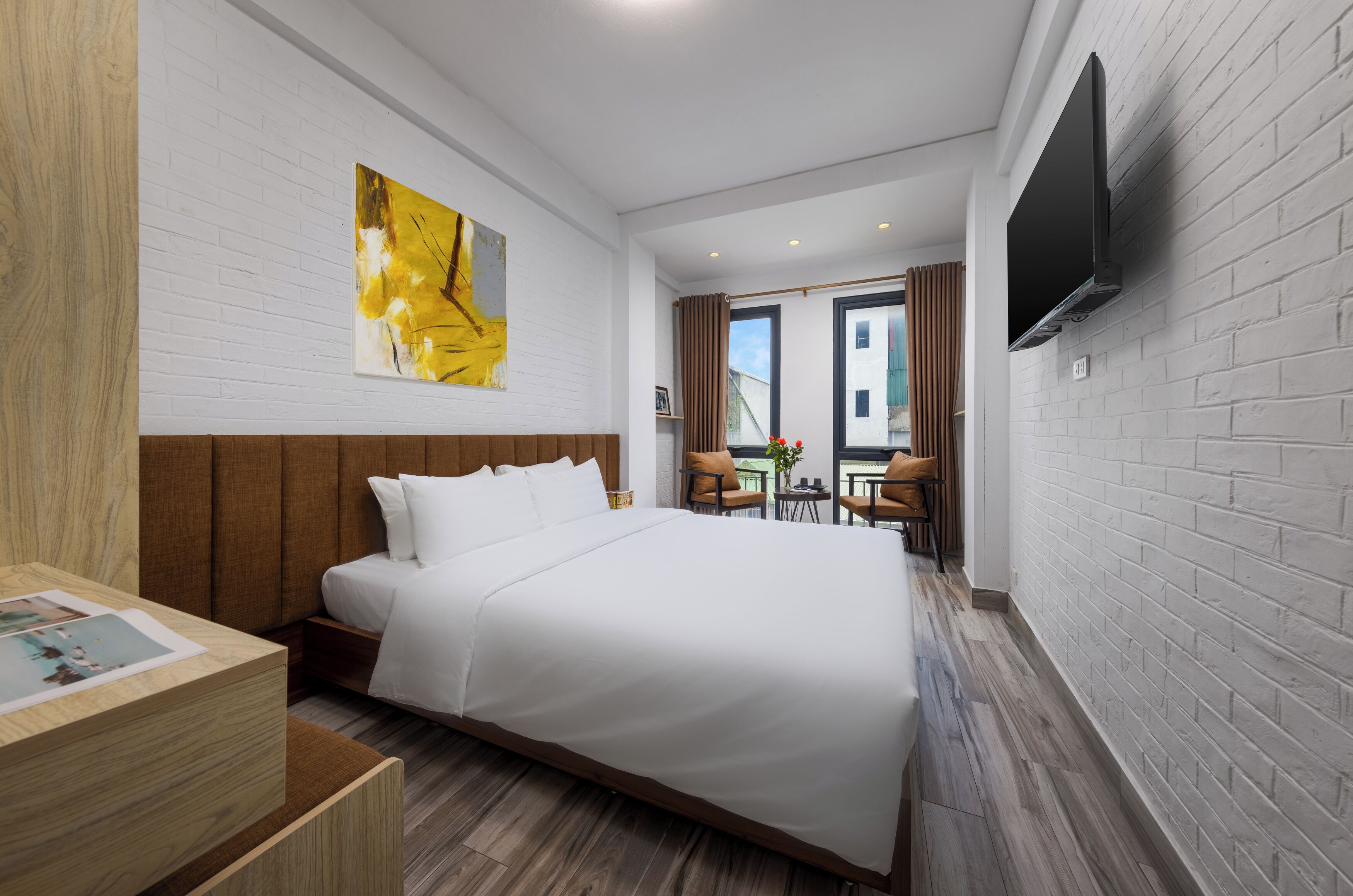 Habitación de hotel con una cama grande, un televisor de pantalla plana en la pared, un cabecero de madera y vistas al exterior a través de una ventana.