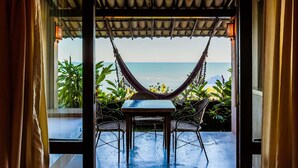 A hammock chair and table setup facing a beach view. - Baixu Village (Porto Seguro)
