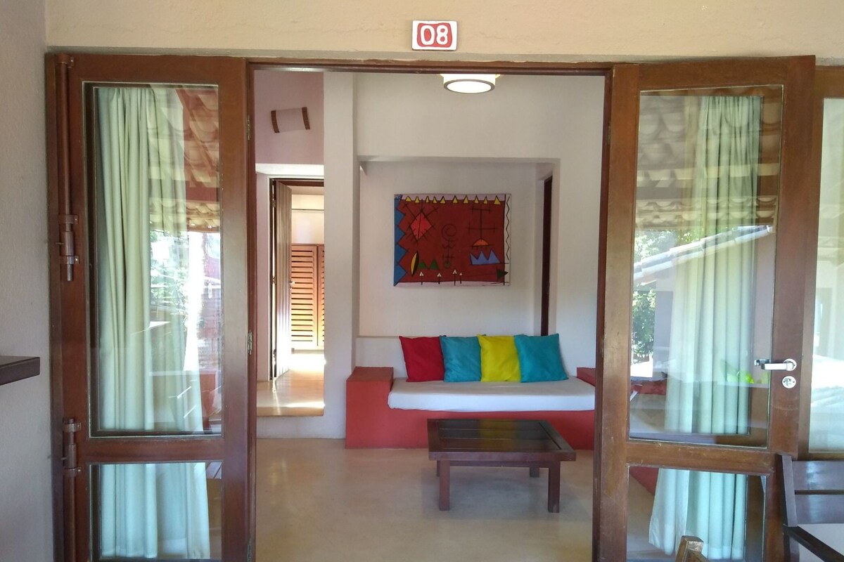 A room with a sofa, a table, and a wall-mounted artwork.