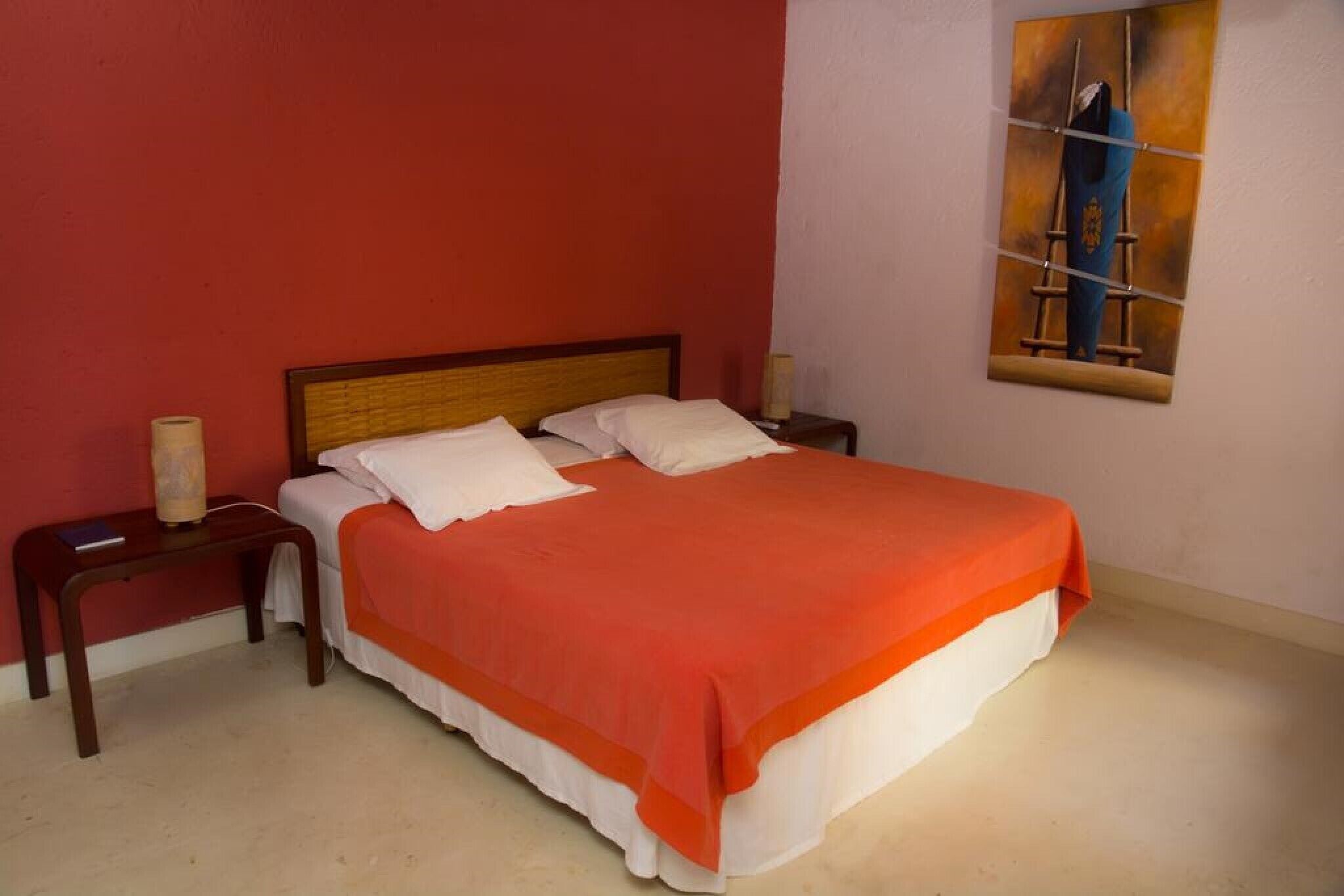 A bedroom with a bed, two bedside tables, a nightstand, and a painting on the wall.