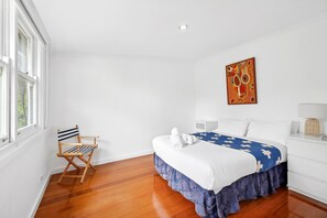 A hotel room with a bed, a chair, a bedside table, and a painting on the wall. - Surphy G (Anglesea)