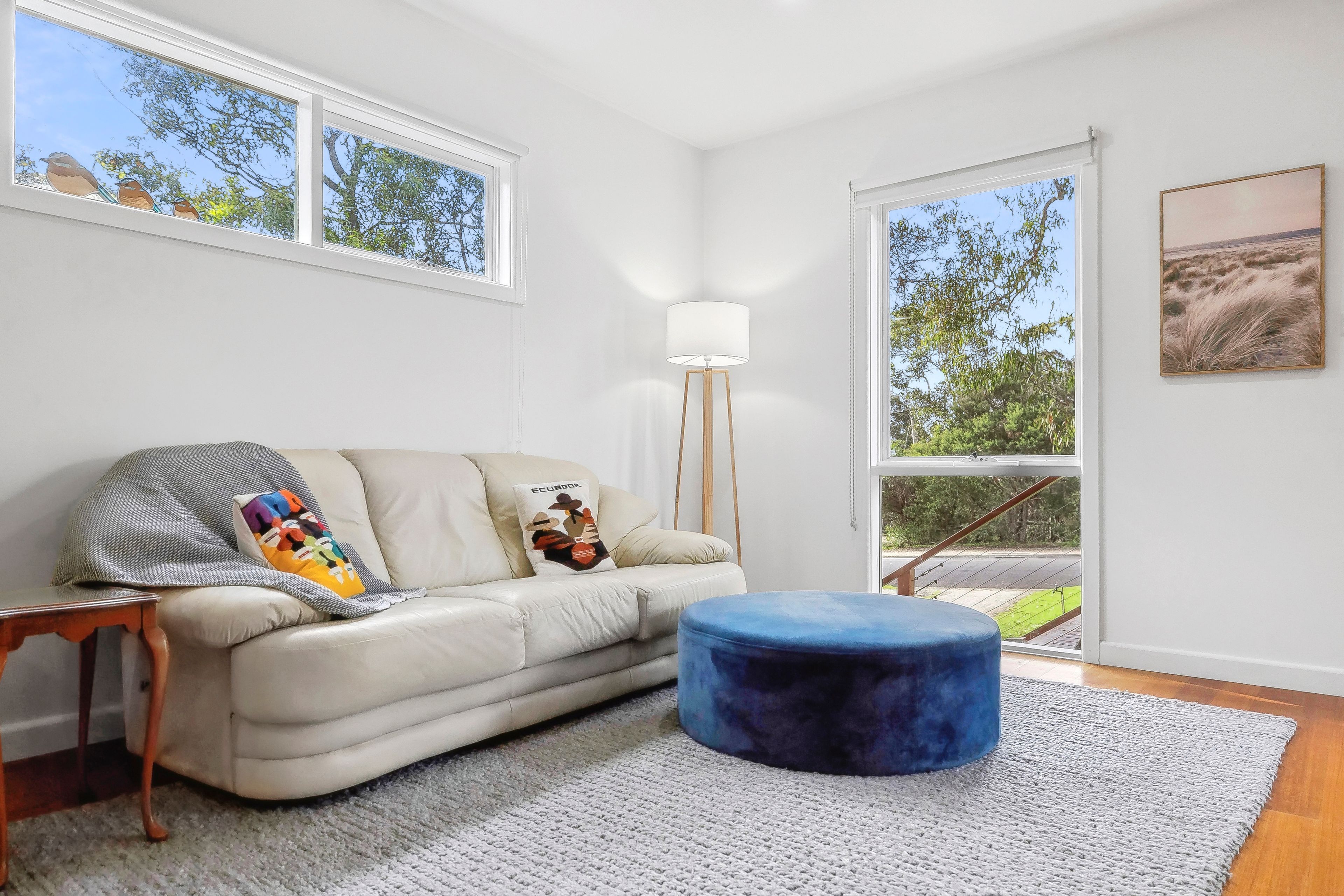 A modern living room with a sofa, ottoman, and a floor lamp.