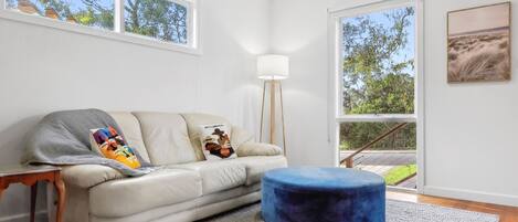 A modern living room with a sofa, ottoman, and a floor lamp.