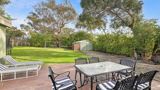 A patio with a table and chairs, a small shed, and a lawn. - Surphy G (Anglesea)