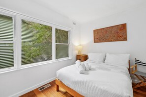 Un dormitorio con una cama, una mesita de noche, una lámpara y una obra de arte en la pared.