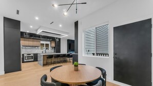 Una cocina moderna con una isla central, electrodomésticos integrados y un comedor con una mesa redonda y sillas.