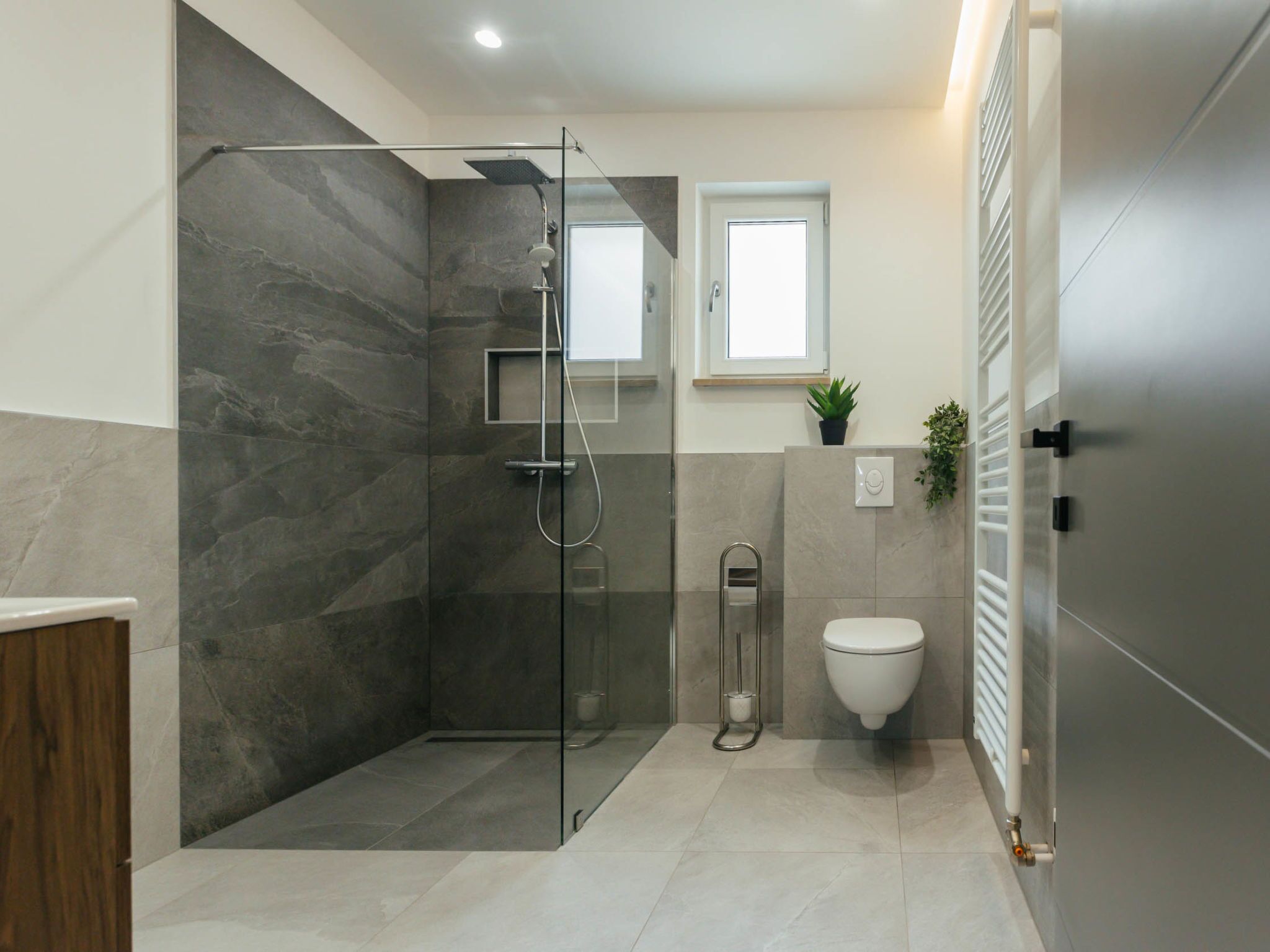 Een moderne badkamer met een douchecabine van glas, een toilet en een klein raam.