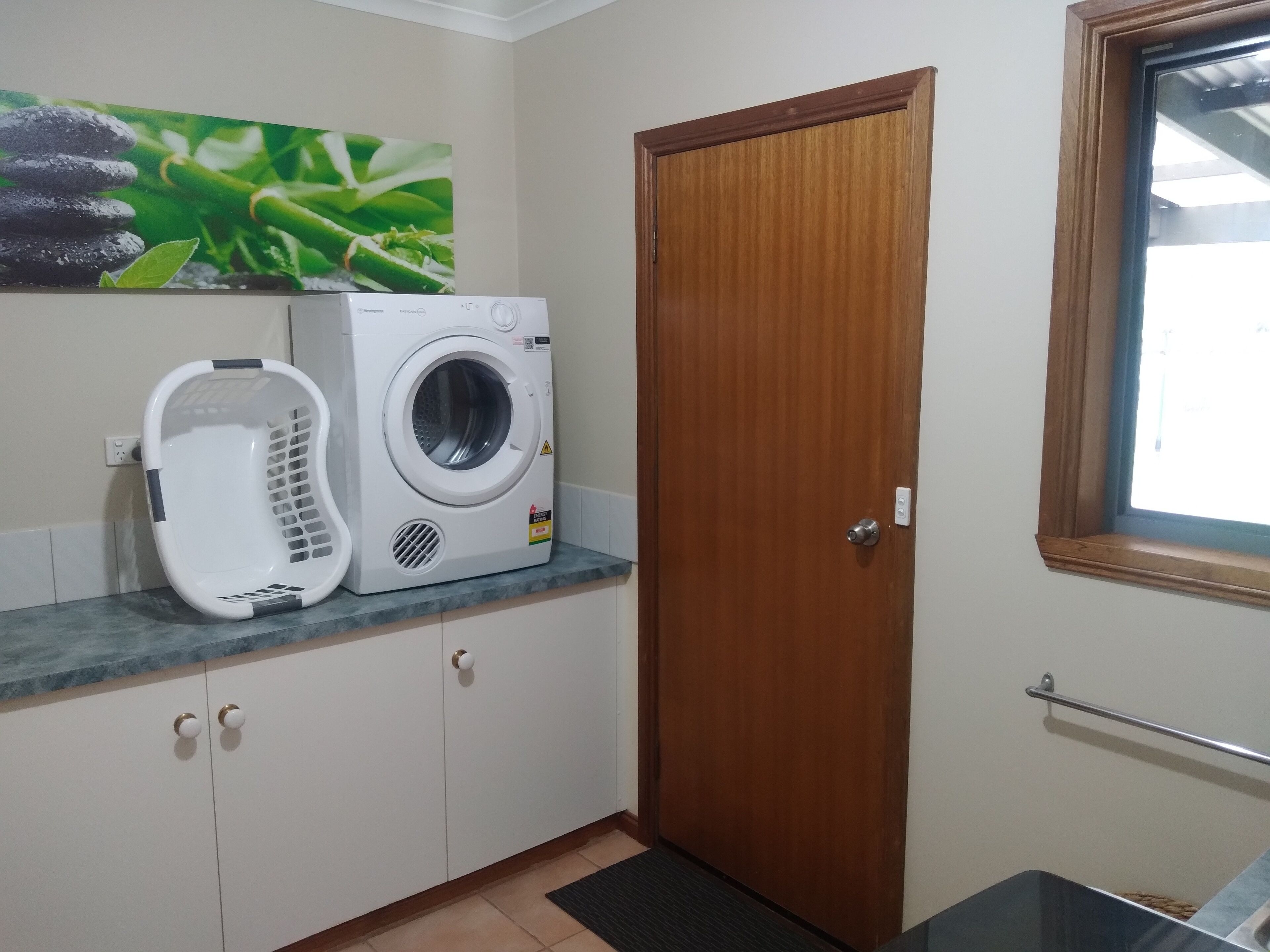 A laundry area with a washing machine, a drying rack, and a wooden door.