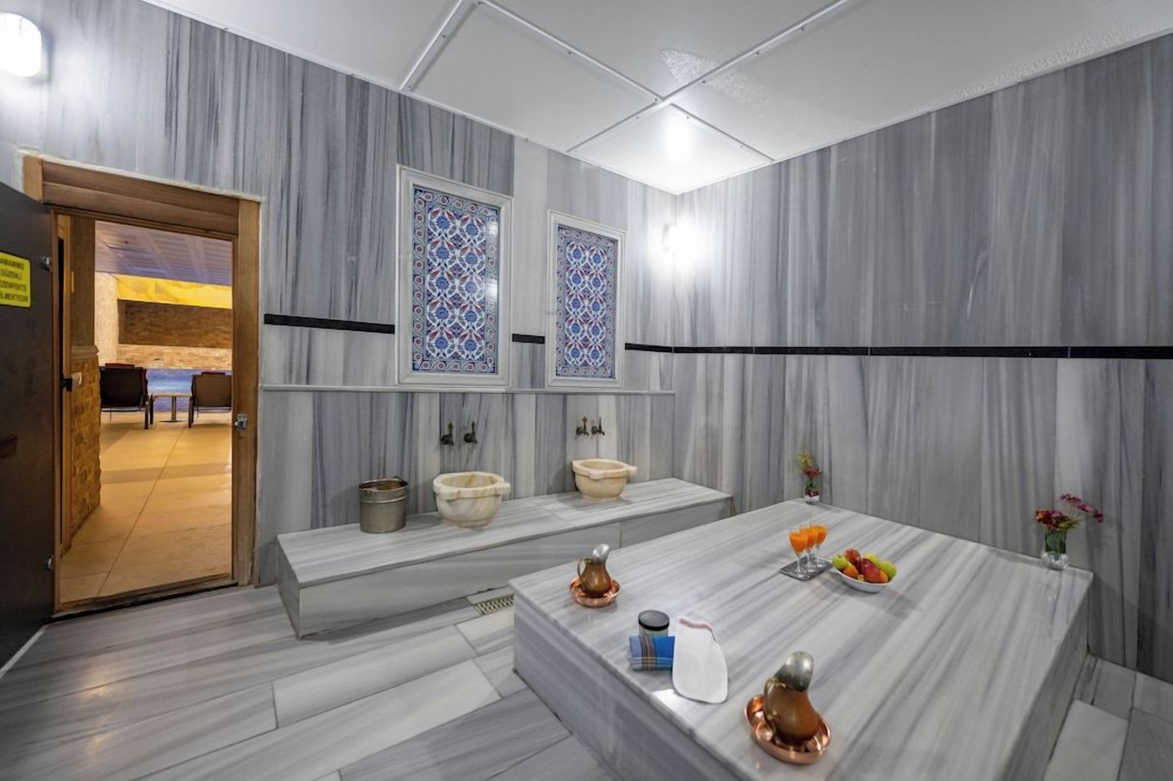 Ein modernes Badezimmer mit Marmorwänden, einem Waschbecken und einem Schminktisch mit Toilettenartikeln.