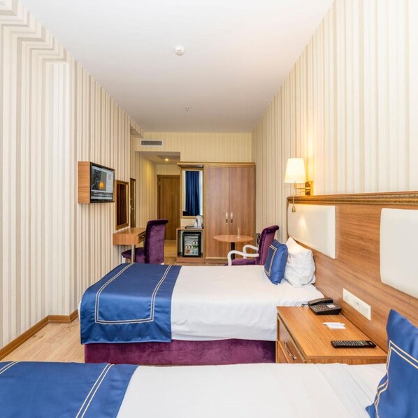 A hotel room with two beds, a desk, a chair, a minibar, and a mirror. - Interstellar Hotel (Istanbul)