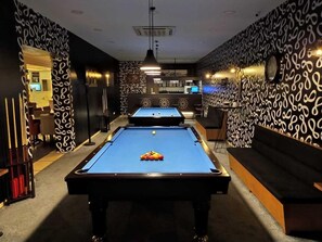 A pool table with balls and cues, a bar area with a counter and stools, and patterned walls. - Interstellar Hotel (Istanbul)