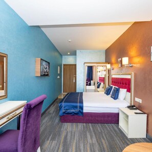 Una habitación de hotel con una cama, un escritorio, una silla y un espejo.