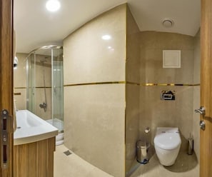 A bathroom with a glass-enclosed shower, a white sink, and a toilet. - Interstellar Hotel (Istanbul)