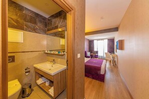 Ein Hotelzimmer mit Bad, einem Bett, einem Schreibtisch und einem Sessel.