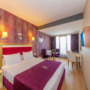 A hotel room with a large bed, a desk, and a chair. - Interstellar Hotel (Istanbul)