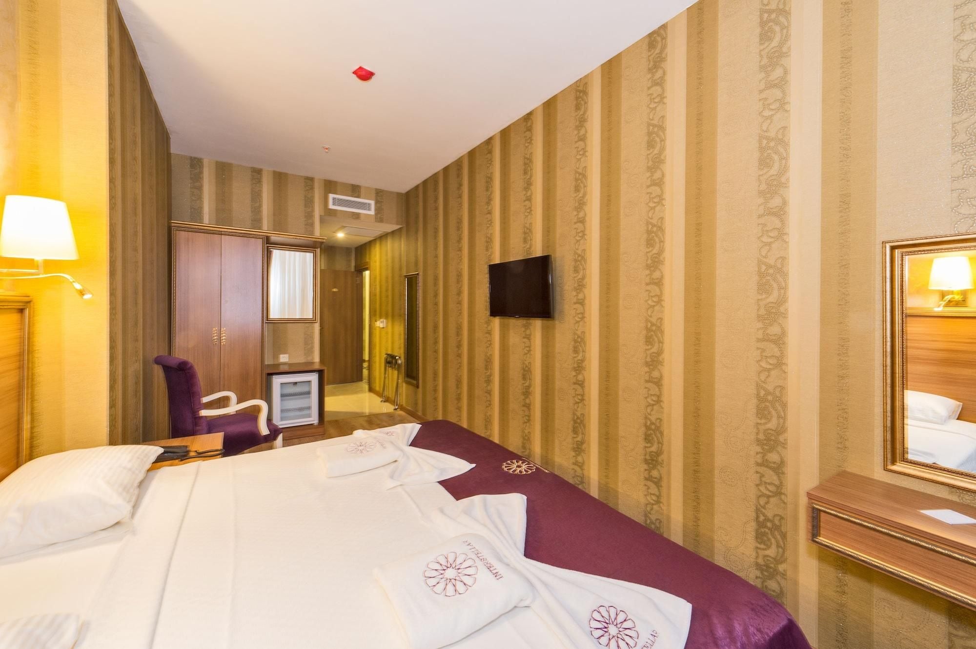 A hotel room with a bed, a desk, a chair, a TV, and a mirror.