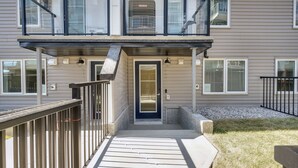 A two-story building with a dark front door, a small porch with a metal railing, and a mailbox. - Cozy Place to Stay in South Calgary (Calgary)