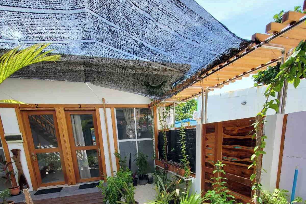 A covered patio area with potted plants, a wooden deck, and a pool.